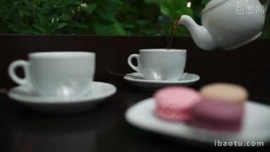 在咖啡馆里，把茶倒进两个白色的<strong>杯子</strong>里，然后专注于手拿美味的马卡龙